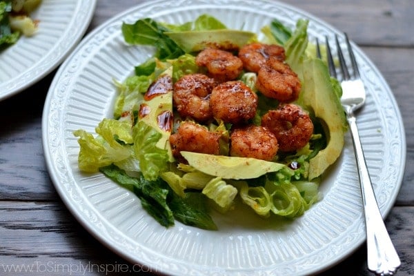 A plate with salad topped with spicy shrimp and avocado