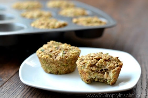 These Zucchini Banana Oatmeal Muffins are an incredible, healthy breakfast. Made with no refined sugar, oil or flour, they are wonderfully moist and perfect for on the go. two oatmeal zucchini muffins on a white plate with muffin tin in the background