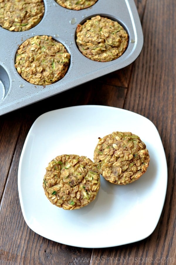 Zucchini Banana Oatmeal Muffins are an incredible, healthy snack. overhead of two Zucchini Banana Oatmeal Muffins on a white plate with muffin tin beside