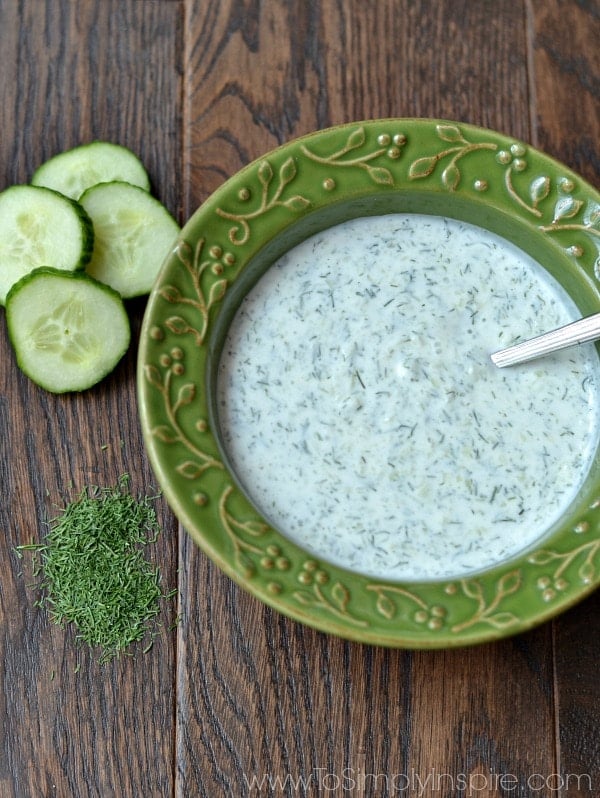 A green bowl of Cucumber Dill sauce on a wood table