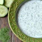 A green bowl of Cucumber Dill sauce on a wood table