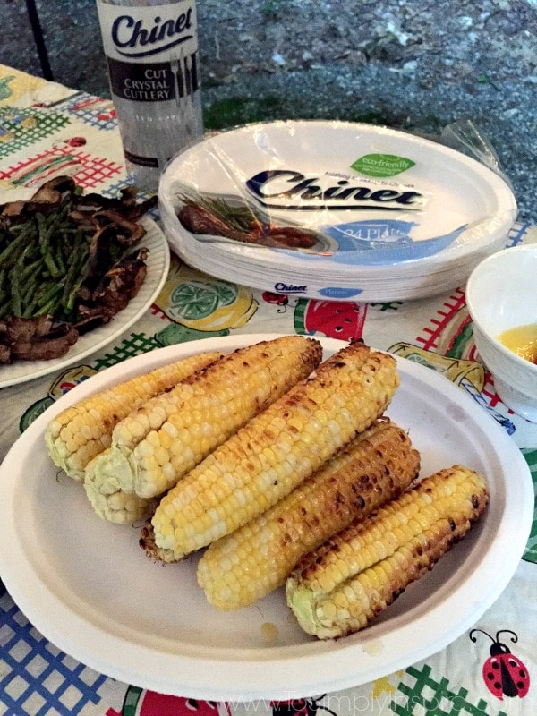A plateful of grilled corn on the cob with chines plates in the background. 