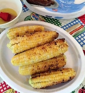 A white plate full of grilled corn on the cob