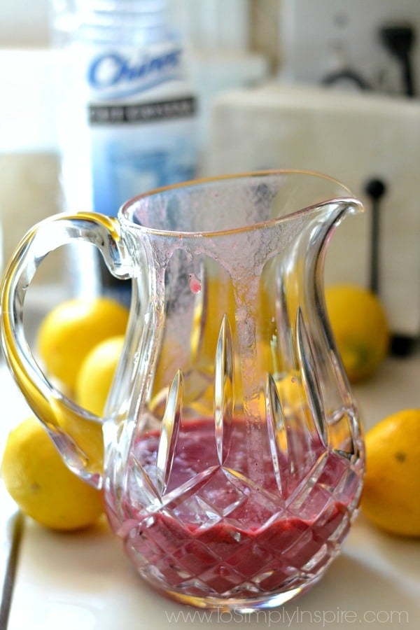 a pitcher with red drink surrounded by lemons