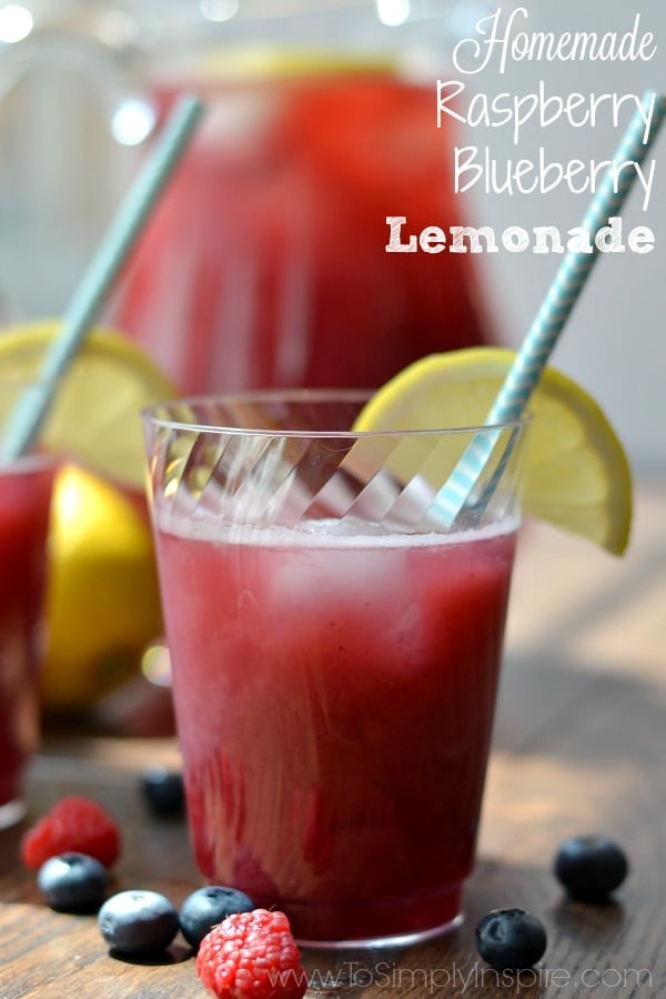 A close up of a cup of raspberry blueberry lemonade with a light blue straw and a lemon wedge with text overlay