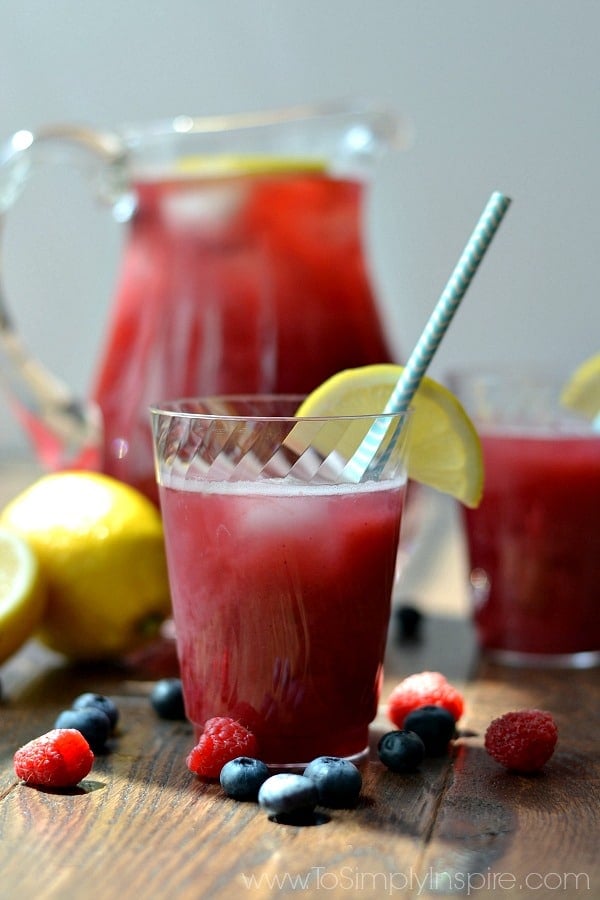 several cups of punch on a table with a pitcher in the background