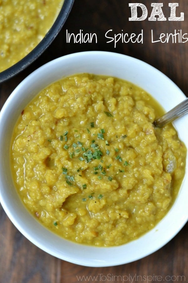 A closeup of Lentil stew with a spoon in a white bowl