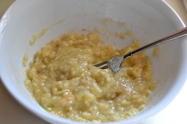 Mashed bananas in a white bowl with a fork