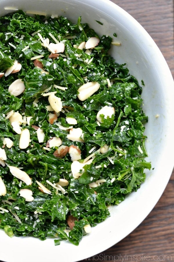 A bowl of kale salad with slices of almonds