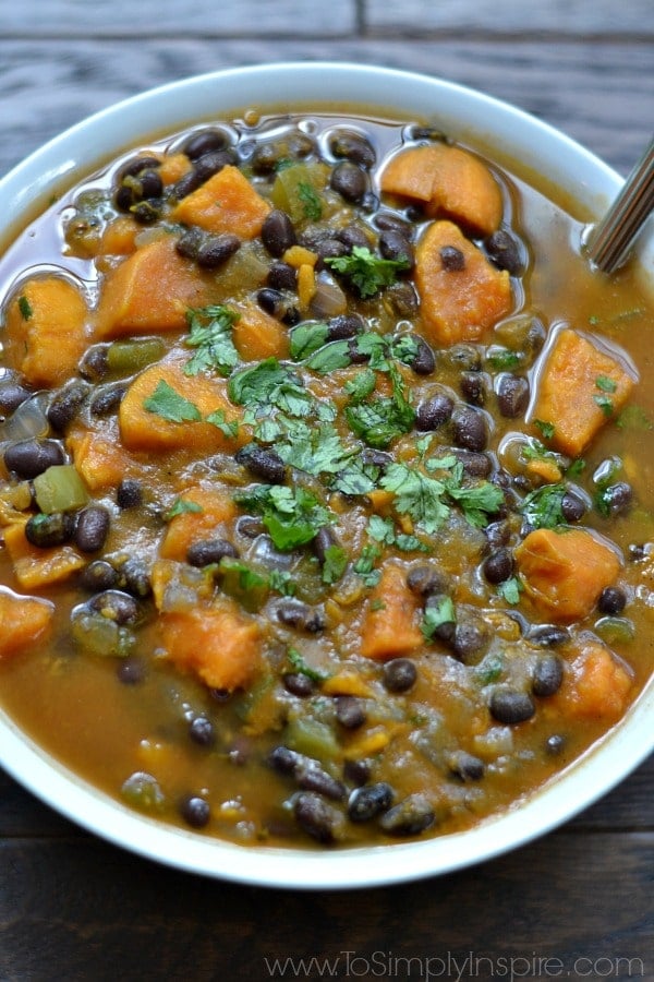 closeup of sweet potato and black bean soup in a white bowl topped with cilantro