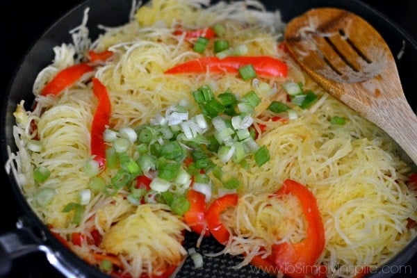 A pan filled with Spaghetti squash, red pepper slices and green onions