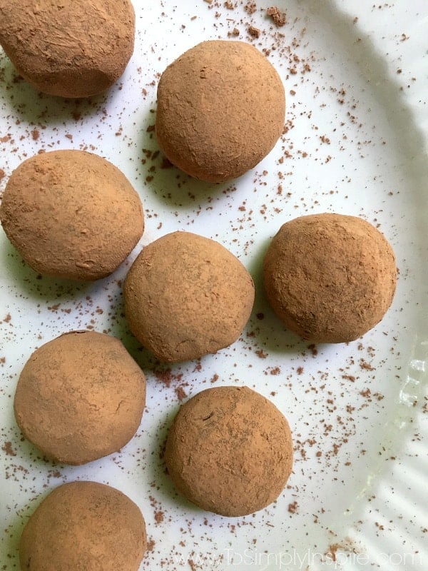 A close up chocolate truffles covered with cocoa powder on a white plate