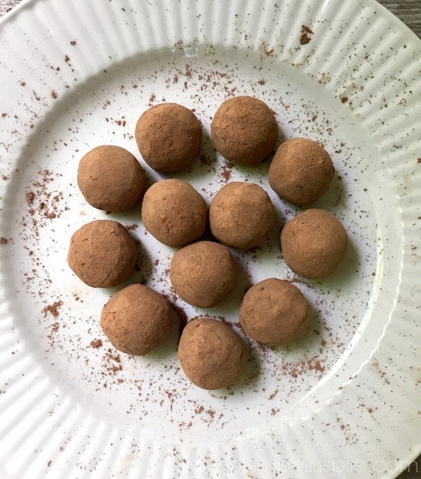 a white plate full of cocoa covered chocolate truffles