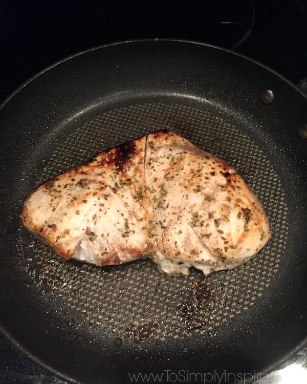 a swordfish steak cooking in a black pan