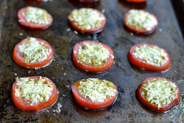 a pan full of sliced tomatoes with parmesan cheese on top