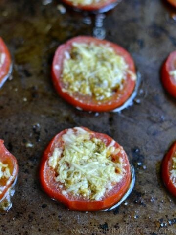 two slices of tomato on a baking sheet topped with parmesan cheese