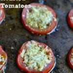 closeup of two tomatoe slices with parmesan cheese and pesto on top