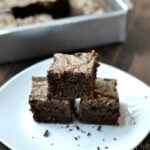 a stack of three brownies on a white plate