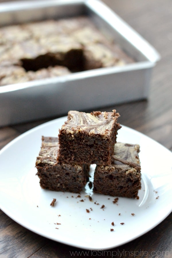 a stack of three brownies on a white plate with baking dish in background