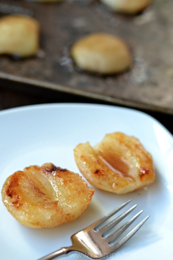closeup of two baked pears on a white plate with a fork
