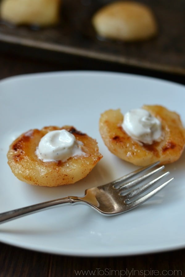 closeup of two baked pears with vanilla ice creams on a white plate with a fork