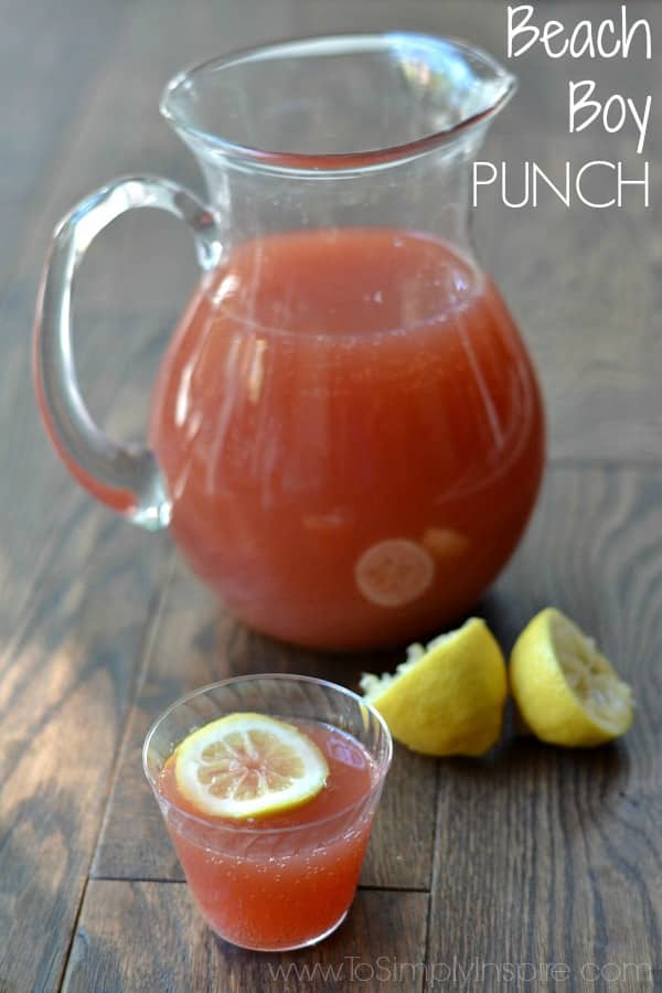 A pitcher of red punch with a cup in front