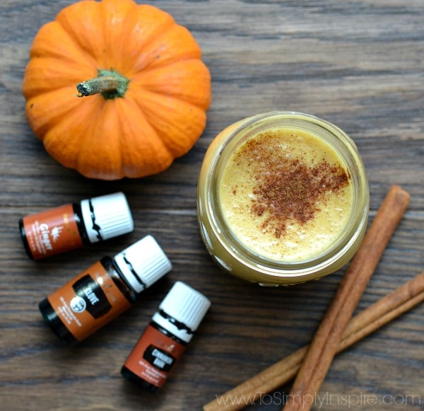pumpkin creamer in a mason jar with cinnamon sticks and small pumpkin with 3 essential oil bottles