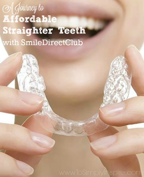 closeup of woman smiling holding invisible teeth aligners in her fingers