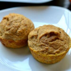 Two pumpkin protein muffins on a white plate.