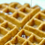 pumpkin waffles on a plate with syrup being poured over and text overlay that reads homemade pumpkin waffles