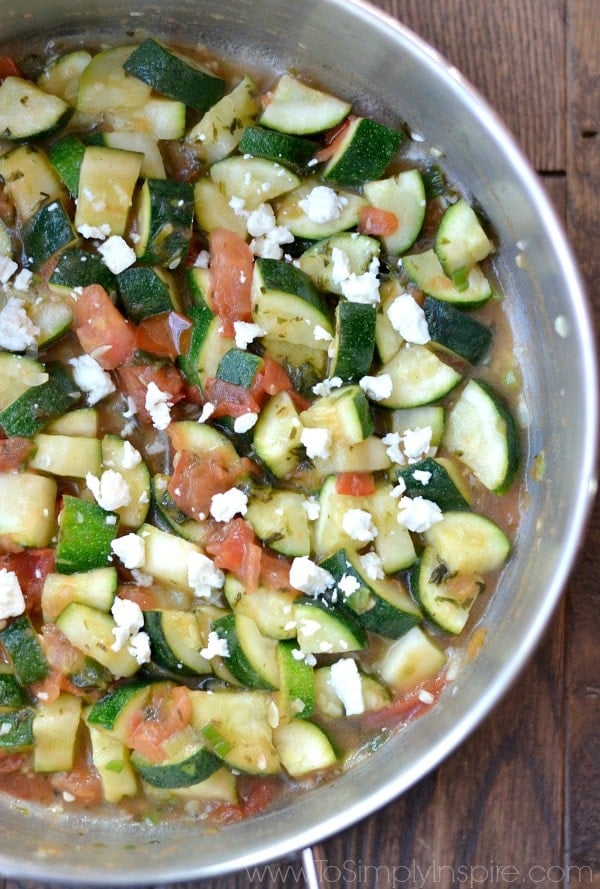 A silver pan with diced zucchini, feta cheese and diced tomatoes