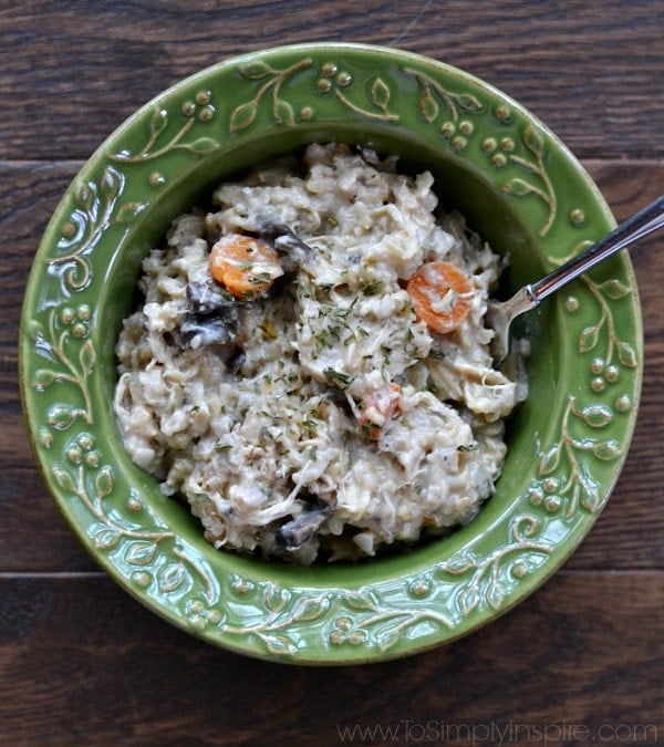 overhead of a green bowl of creamy chicken and brown rice casserole with a spoon