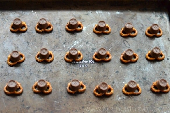 a bunch of pretzel knots topped with a rolo candies on a baking dish