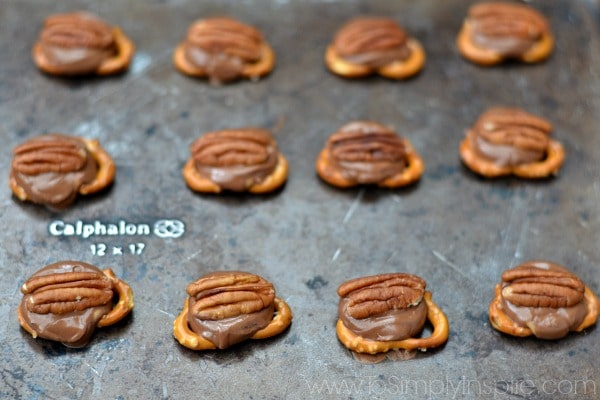 a bunch of pretzel knots topped with a roll and a pecan half on a baking sheet