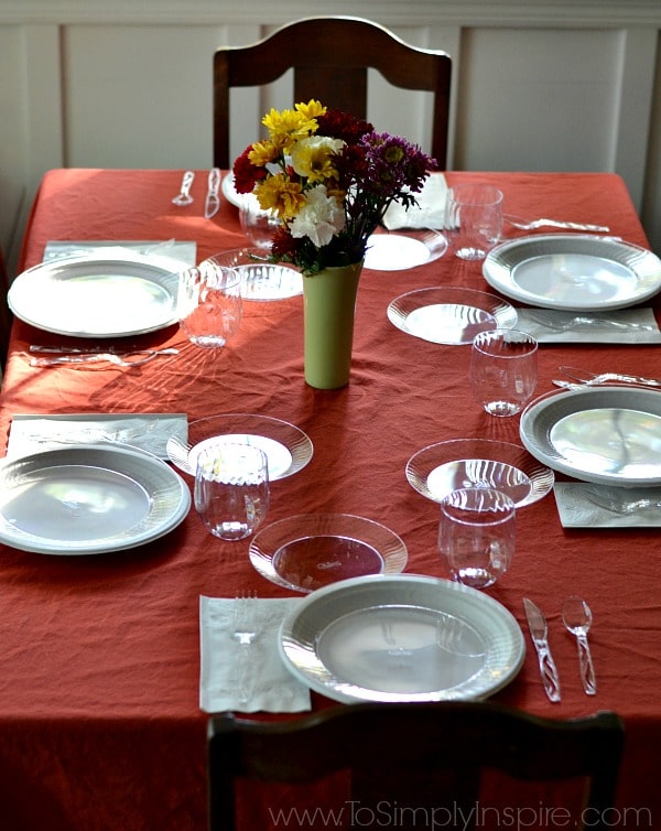 A dining table with a red table cloth set with dishes