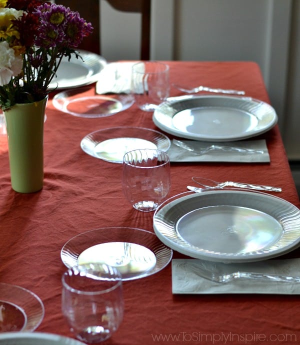 A table set with dishes and a vase of flowers