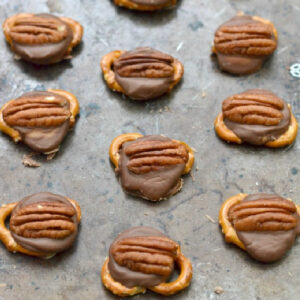 pretzel knots topped with a rolo candy and a pecan half