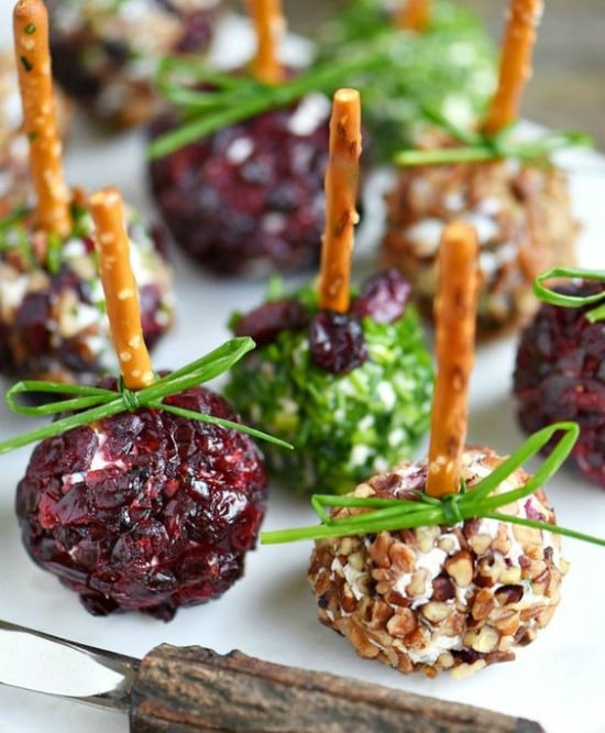 A close up of a plate with mini cheese balls with pretzel sticks