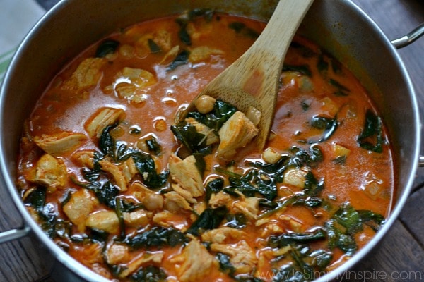 a closeup of soup in a pot with Chicken, spinach and Chickpeas with wooden spoon