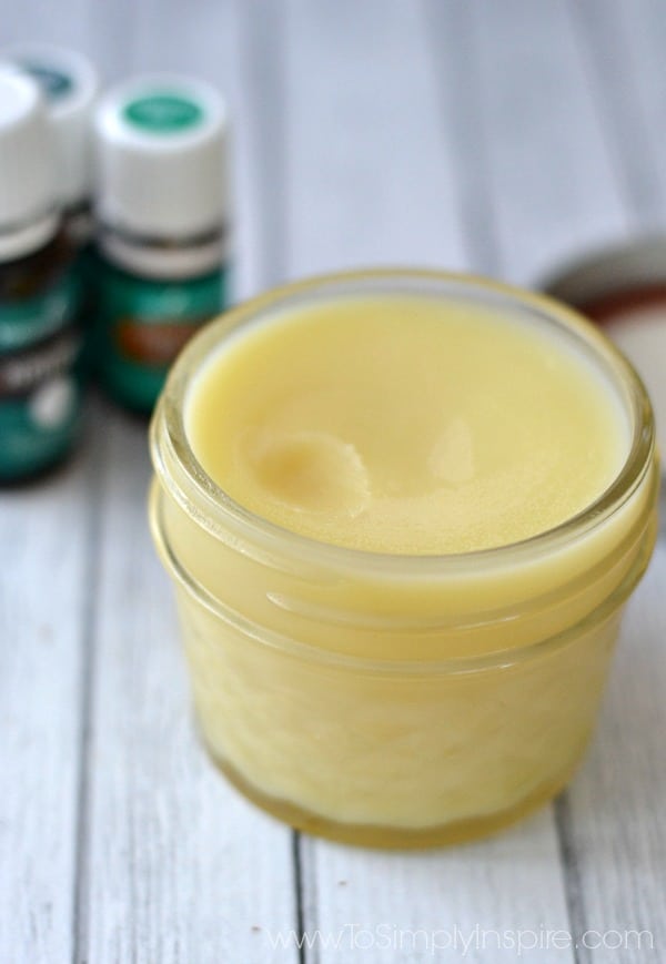 a small mason jar with homemade chest rub with essential oil bottles in the background