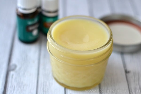 a small mason jar with homemade chest rub with essential oil bottles in the background