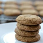 A close up of a stack of 4 molasses cookies with a cooling rack.
