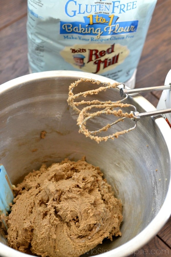 cookie dough in a silver mixing bowl with beaters leaning on the bowl.