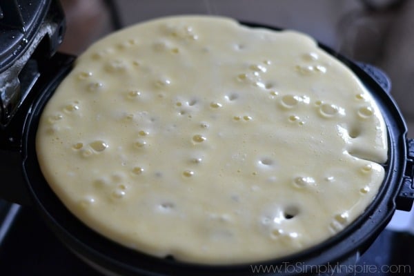protein waffle batter cooking on a black waffle iron