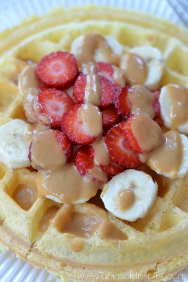 Closeup of low carb Protein Waffles topped with sliced strawberries and bananas drizzled with peanut butter.