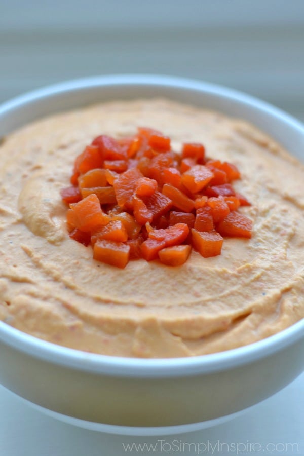 a white bowl with Hummus  topped with  Roasted Red Peppers