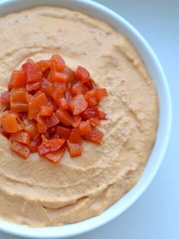 closeup of Roasted Red Pepper Hummus recipe in a white bowl