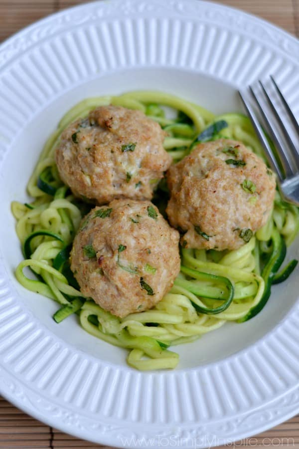 three Asian Turkey Meatballs over zucchini noodles on a white plate.