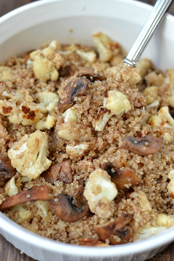 Quinoa, cauliflower and mushrooms in a white bowl with a spoon