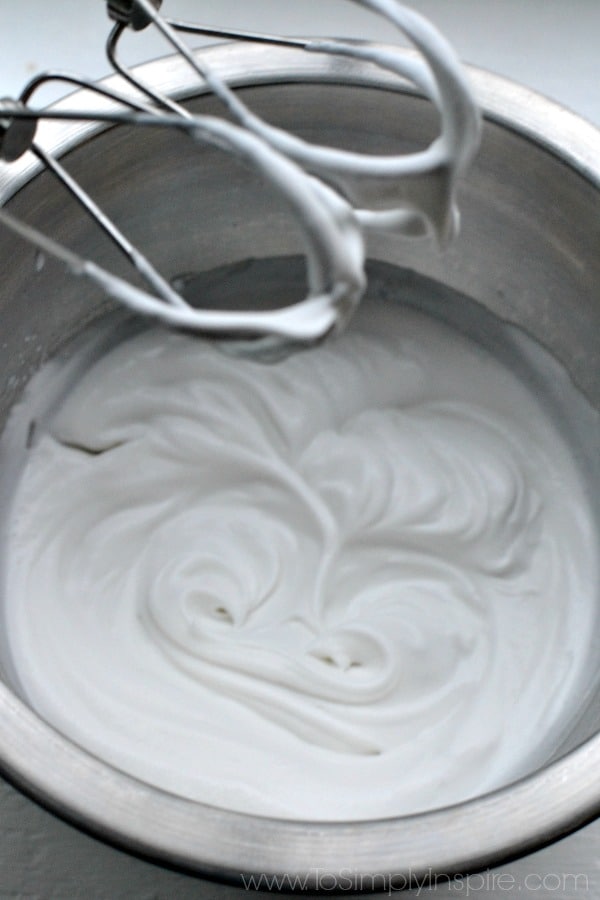 whipped coconut milk in a silver mixing bowl with beater over top